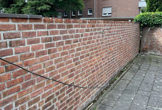 zeigt die Mauer, welche einen Parkplatz abgrenzt, von welcher das Kupferabdeckblech entwendet wurde